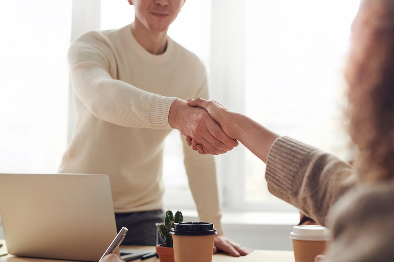 Two professionals shaking hands over a desk